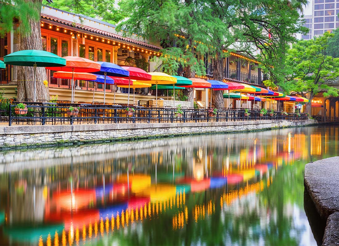 Insurance Solutions - Scenic View of the River Walk with Colorful Umbrellas and Seating by the Water Below Large Trees in Downtown San Antonio Texas