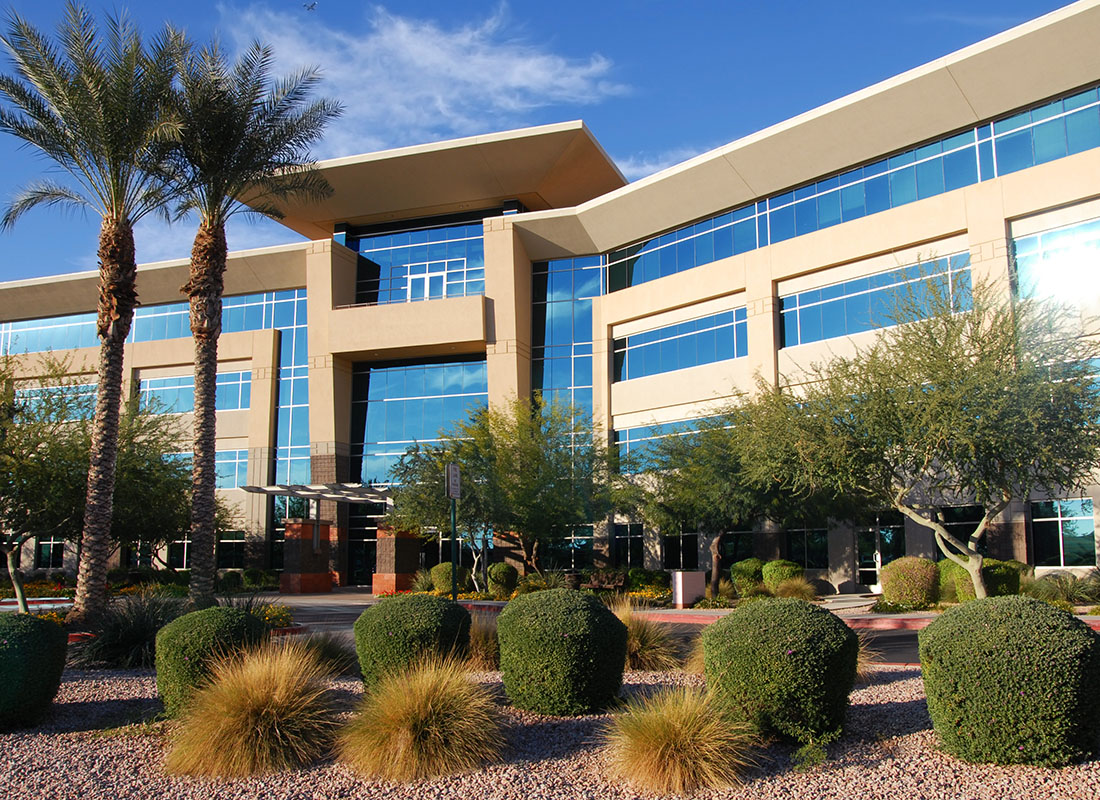 Insurance by Industry - Exterior View of a Modern Commercial Building Against a Blue Sky with Palm Trees and Decorative Landscaping in the Front